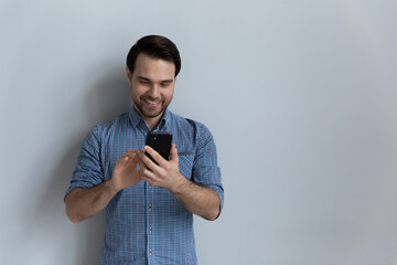 Wall Mural - happy millennial man using online app on smartphone, reading text message on mobile phone screen, ch
