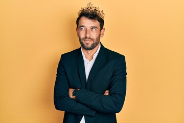 Poster - Handsome man with beard wearing business suit with arms crossed gesture and king crown smiling looking to the side and staring away thinking.