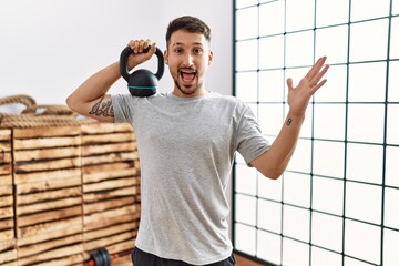 Canvas Print - Young handsome man wearing sportswear using dumbbells celebrating victory with happy smile and winner expression with raised hands