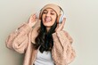 © Krakenimages.com - Young hispanic woman listening to music using headphones smiling and laughing hard out loud because funny crazy joke.