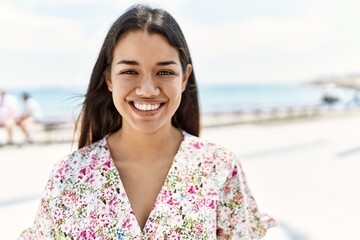 Sticker - Young latin girl smiling happy standing at the beach.