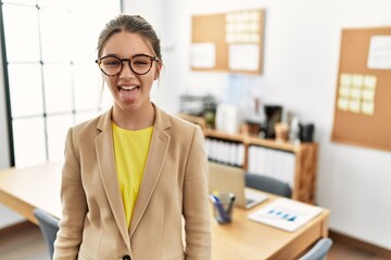 Poster - Young brunette teenager wearing business style at office sticking tongue out happy with funny expression. emotion concept.