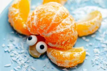 Fruit turtles, a snack made of fresh parts of mandarins served in the shape of water turtles on a blue plate