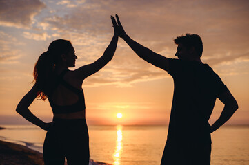 Profile couple young two friend woman man in sport clothes train meet together greet give high five clapping hand folded on sunrise over sea ocean beach outdoor jog on seaside in summer day morning.