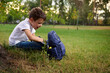 © Taras Grebinets - Elementary aged school boy in casual denim resting on green grass after his first day at school. Adorable child with school bag during recreation on beautiful sunny day. Back to school concept