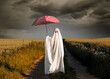 cute ghost in a bed sheet with umbrella on a wheat field