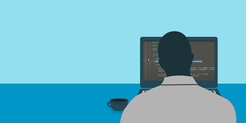 A young programmer sits in front of a laptop and writes the program code.