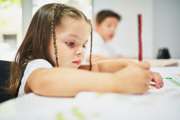 Wall Mural - Young spanish girl writing on notebook with pencil at class