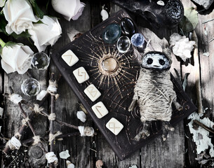 Grunge still life with voodoo doll, decorated witch book, runes and pentagram on planks.