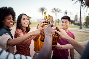  Close-up of hands of a group of young people of different races toasting happily at sunset. Cheers.