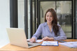 © Prathankarnpap - Attractive businesswoman working with laptop computer and reading financial reports at office.