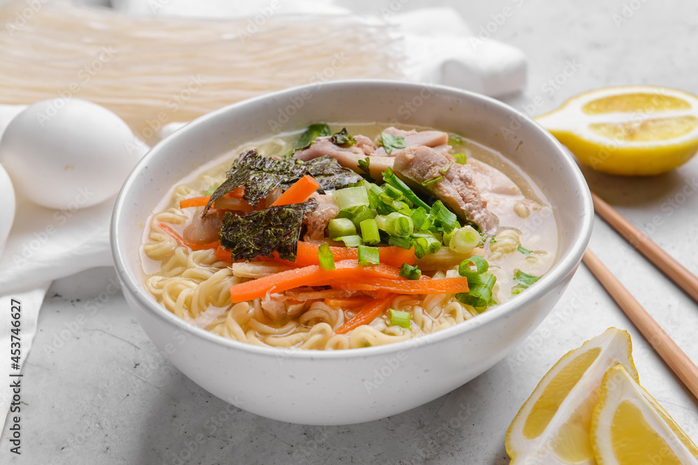 Tasty Chinese soup with chicken in bowl on light background
