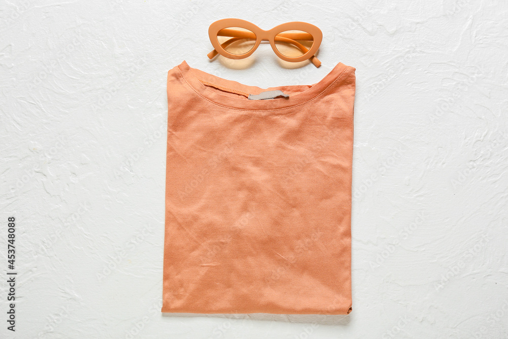 Stylish t-shirt and sunglasses on light background