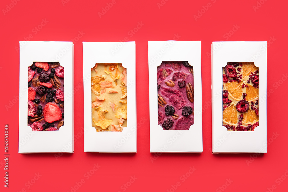 Handmade chocolate bars with fruits and berries on color background