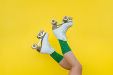 Young Woman Legs With Vintage Quad Roller Skates On Yellow Background