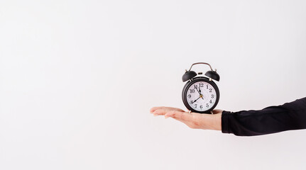 Female hand holding white alarm clock on white background