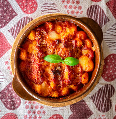 Gnocchi alla Sorrentina, Italian Potato Dumplings in Tomato Sauce, Gratinated With Mozzarella Cheese in a Terracotta Dish.