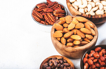 Wall Mural - Nuts in bowls. Almonds, hazelnuts, walnuts and other. Healthy food snack mix on white table, top view, copy space