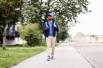 Wall Mural - food shipping, profession and people concept - happy smiling indian delivery man with thermal insulated bag and smartphone walking along city street