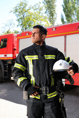 Wall Mural - Portrait of firefighter in uniform with helmet near fire truck outdoors