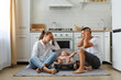 © sementsova321 - Portrait of mother and father sitting on floor in kitchen with little son or daughter in rocking chair on kitchen floor, tired sleepless parents keeping hands on head, need rest.