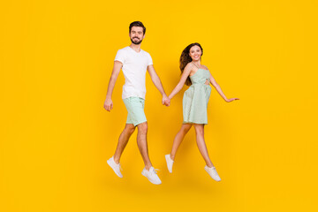 Sticker - Photo of cheerful carefree couple jump hold hands move go wear casual outfit isolated yellow color background