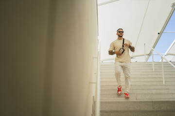 Sticker - Young caucasian stylish guy with tattoos and sunglasses standing on the stair