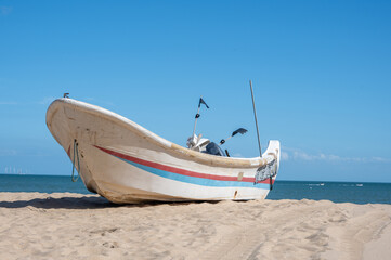 Striped boats docked on the beach, blue sky, sea and beach