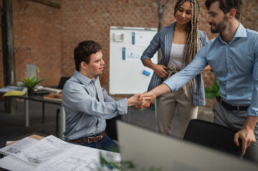 Down syndrome man shaking hands with businesspeople in office, social inclusion and cooperation concept.