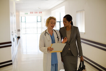 Wall Mural - Doctor and businesswoman walking in hospital corridor