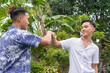 Two Filipino mean fist bumps showing respect or support. Collaborating on a project or greeting each other. Gen Z generation.