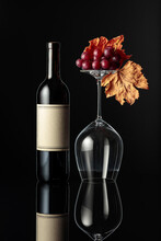 Bottle Of Red Wine And An Inverted Wine Glass On A Black Background.
