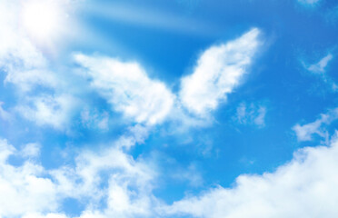 Silhouette of angel's wings made of clouds in blue sky