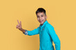 Young smiling teenage boy  gestures a sign  victory or pease against a yellow background.