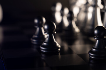 Canvas Print - Closeup shot of chess pieces on the board on a black background