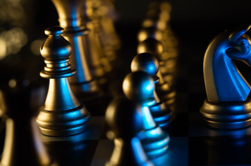 Canvas Print - Closeup shot of chess pieces on the board in the blue light on a black background