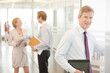 © KOTO - Businessman smiling in office hallway