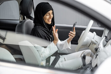 Wall Mural - Muslim woman talks on phone while driving a car