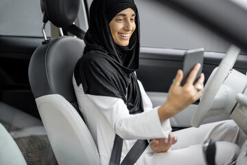 Wall Mural - Muslim woman talks on phone while driving a car