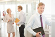 © KOTO - Businessman smiling in office hallway