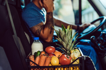 Wall Mural - Young bearded man is talking on phone while driving delivery van. He is working in everyday or daily home delivery service.