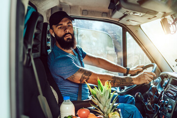 Wall Mural - Young bearded man is driving delivery van. He is working in everyday or daily home delivery service.