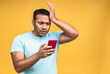 © denis_vermenko - Portrait of african american indian black man, shocked, surprised, wide open mouth, mad by what he sees on his cell phone, isolated on yellow background. Negative human emotions, facial expressions.
