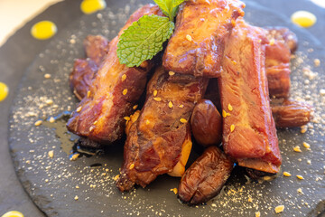 Sticker - Closeup shot of pork ribs with smoked paprika decorated with mint on the ground serving boa