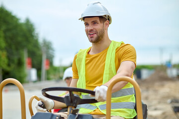 Wall Mural - High-spirited skilled operator driving an earth rammer machine