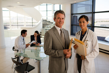 Poster - Doctor and businessman handshaking in hospital lobby
