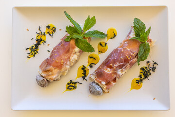 Poster - Closeup shot of a dish with prosciutto rolls decorated with mint and delicious sauce