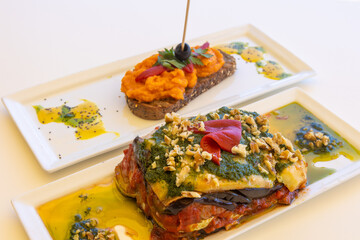 Canvas Print - Closeup shot of plates with eggplant dish and a slice of bread with pumpkin caviar