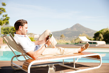 Wall Mural - Man using digital tablet on lounge chair at poolside