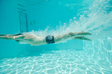 Man swimming underwater in pool